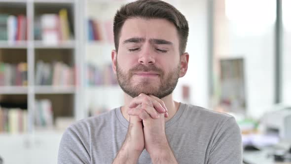 Portrait of Hopeful Young Man Praying with Closed Eyes 