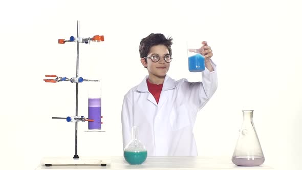 Young Boy Chemist Wearing Uniform, Red Shirt and Round Glasses in Laboratory Making Some Experiment