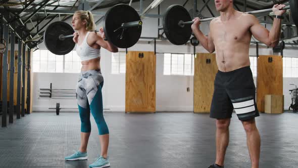 Side view of an athletic Caucasian man and woman squatting