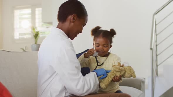 African american girl using stethoscope and smiling during medical home visit