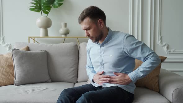 A Man Suffers From Abdominal Pain While Sitting at Home on the Couch