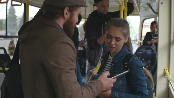 Man Showing Young Woman Something on Tablet