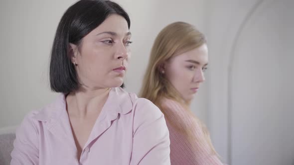 Close-up Portrait of Brunette Caucasian Woman Sitting Back To Back with Blond Girl. Portrait of