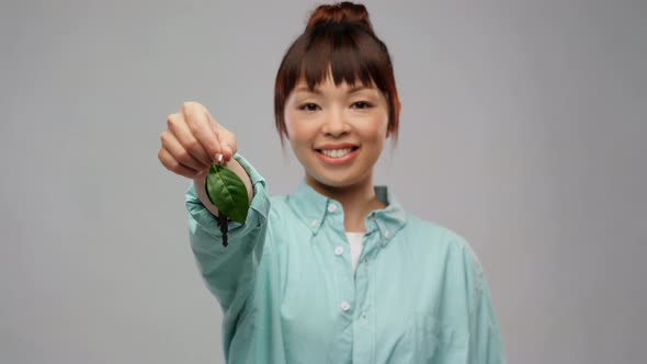 Happy Asian Woman Holding Car Key with Green Leaf