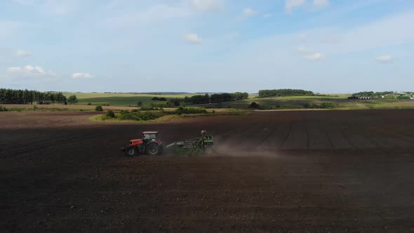 Orange Tractor Plows the Field. Aerial View. 