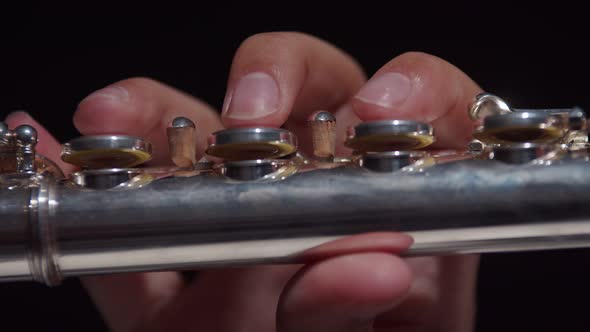 Closeup flute played with fingers by female musician in studio on dark background, slide. Female mus