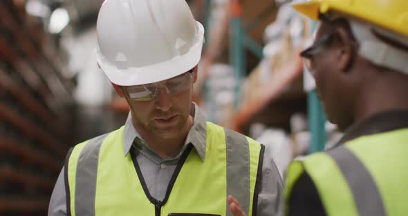 Caucasian male factory worker at a factory wearing vis vests, hard hats and glasses