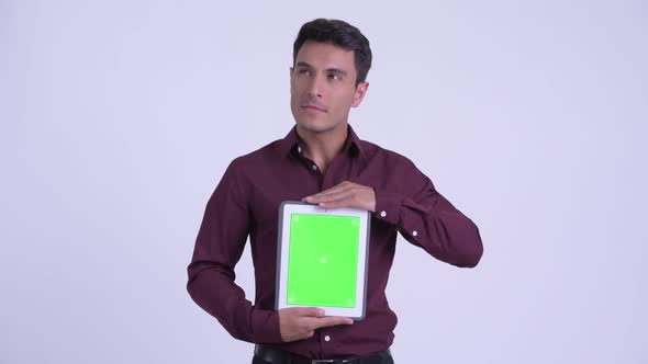 Young Happy Hispanic Businessman Thinking While Showing Digital Tablet