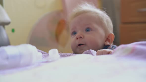 Funny Baby Tries to Climb Up on Soft Bed with Plaid in Room