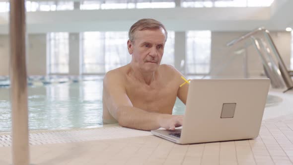 Businessman Using Laptop while Standing in Pool