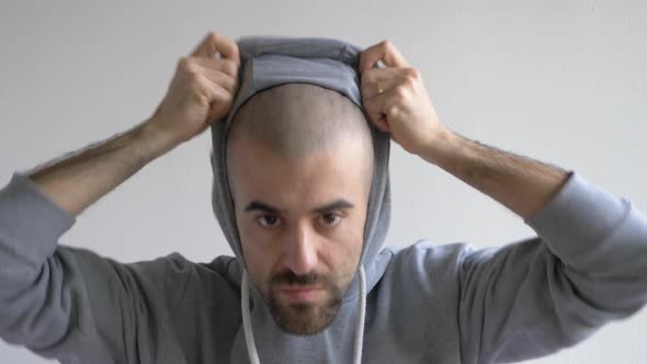 Funny man pulling down hoodie and showing shaven head, slow motion