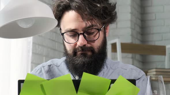 Bearded Man That Works at the Computer Full of Reminder Notes Home Office