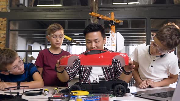 Young Children Using Screwdriver to Disassemble Robotic Machine