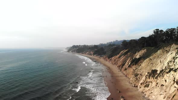 Aerial drone shot over the blue pacific ocean waves off the beach cliffs on the Santa Barbara, Calif