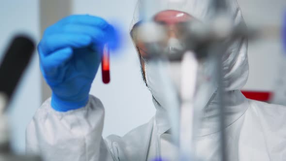 Close Up Chemist Holding Blood Sample Wearing Coverall