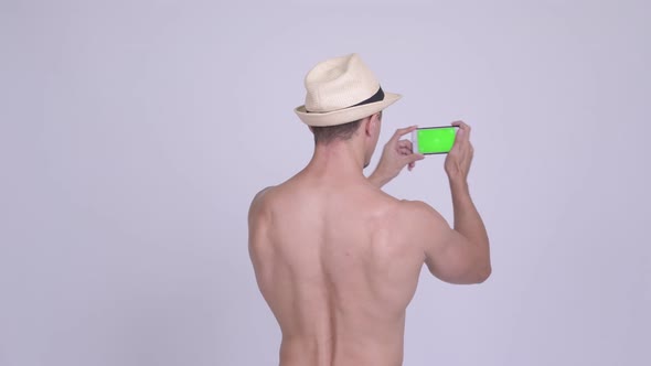 Rear View of Muscular Bearded Tourist Man Taking Picture with Phone