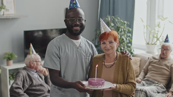 Portrait of Senior Woman with Birthday Cake and African-American Nurse
