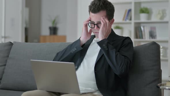 Stressed Young Male Designer with Laptop Having Headache at Home