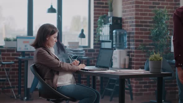 Portrait of Pregnant Woman Working with Charts on Laptop