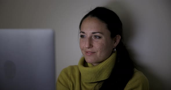 Happy woman with laptop computer on the bed watching movie and navigating onl