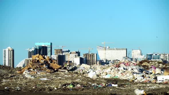 Garbage dump. Skyscrapers, construction site with crane and houses of big city