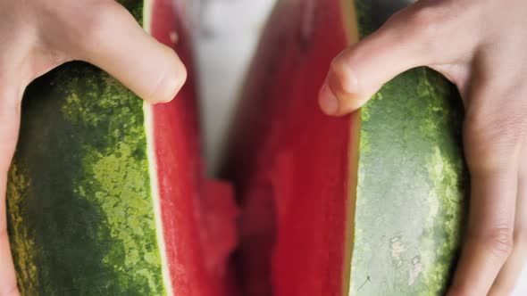 Female Hands Break in Half a Large Ripe Red Watermelon Closeup