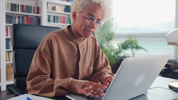 Young African American Woman Freelancer Works Using Laptop Sits at Office Desk