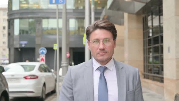 Middle Aged Businessman Walking towards Camera in Street