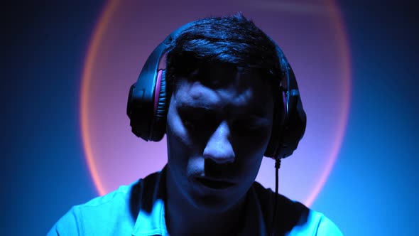 Portrait Man Relaxes Listening to Music Through Headphones in Neon Lighting