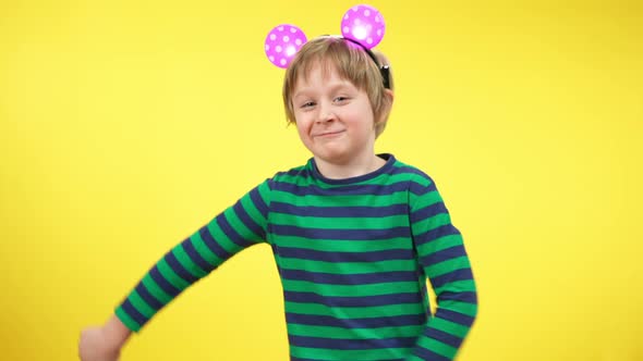 Funny Dance of Cheerful Little Boy Wearing Toy Mouse Ears at Yellow Background