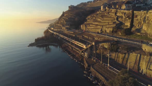 Train Goes Along Lake Geneva Shore at Sunset. Vineyards and Houses. Aerial View