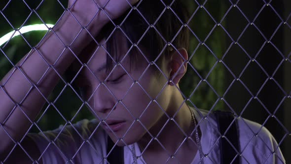 Young Asian Man Behind a Wire Mesh or Fence