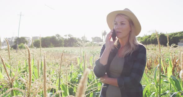 Video of happy caucasian woman using tablet and smartphone in field on sunny day