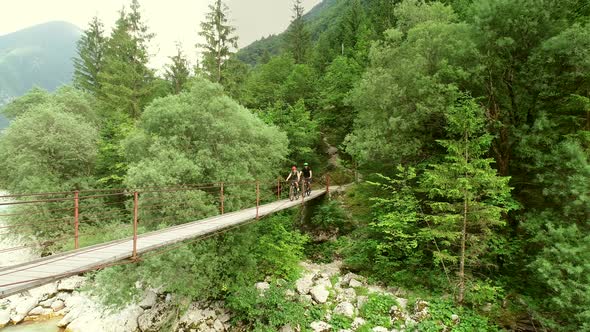 Aerial view of a couple crossing a wooden bridge on bicycles.