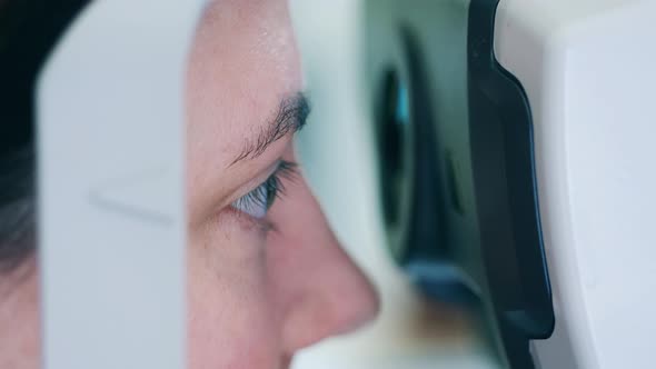 A Woman is Looking Into an Eyesinspecting Machine