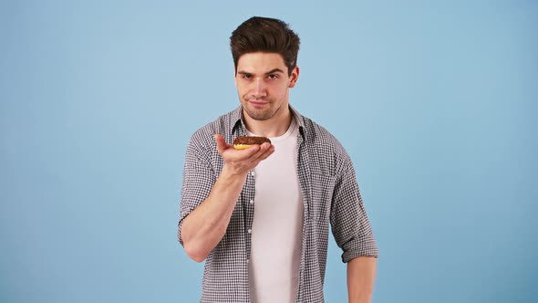 Young Man is Holding Tasty Donut Glazed with Chocolate and Showing Sign No By His Forefinger Does