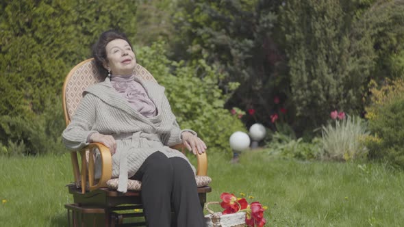 Portrait Cute Happy Mature Woman Sitting on the Lawn in the Rocking Chair Enjoying Sun