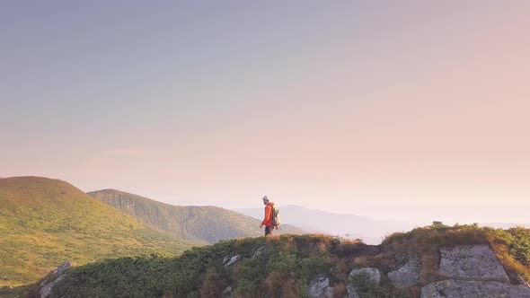 Tourist Hiker with a Backpack in Orange Jacket Walking on Mountain Path in Carpathian Mountains