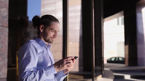 Business Man Using Mobile Phone Near Office Building