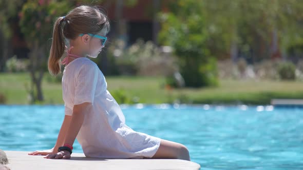 Portrait of Happy Child Girl in White Dress Relaxing on Swimming Pool Side on Sunny Summer Day