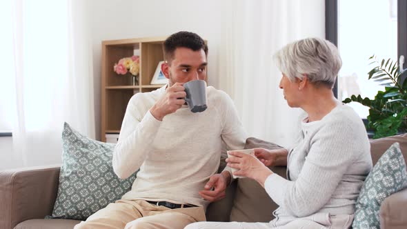 Adult Son and Senior Mother Drink Coffee at Home