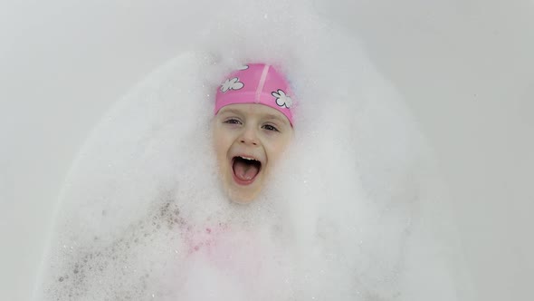 Cute Blonde Girl Takes a Bath in Swimwear. Little Child Washes Her Head