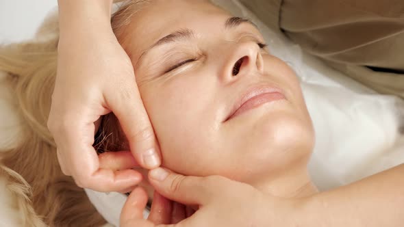 Skilled Beauty Salon Worker Massages Mature Woman Face