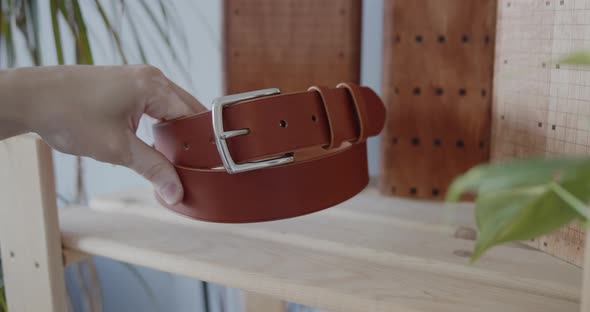 Demonstrating Finished Brown Leather Belt Lying on a Shelf