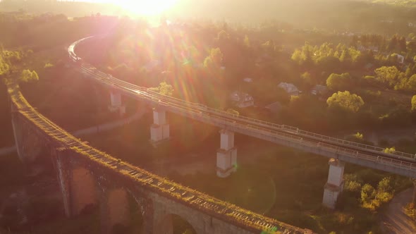 Aerial Shot of a Train Crossing a Beautiful Stone Bridge at Sunset