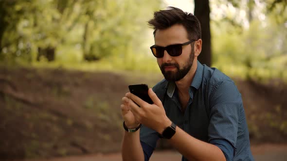 Businessman In Sunglasses Chatting On Mobile Phone With Friend  Sending Message On Social Network.