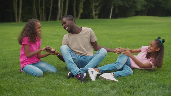 African Dad with Girls Enjoying Leisure Outdoors