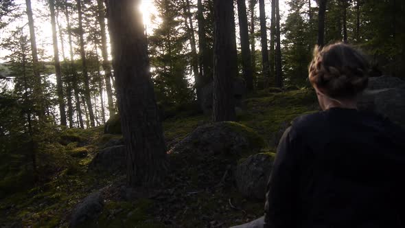 Young woman hiking through a forest near a lake.