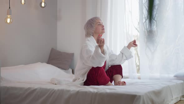 Wide Shot Relaxed Confident Mature Yogi Meditating Sitting on Bed at Home Indoors