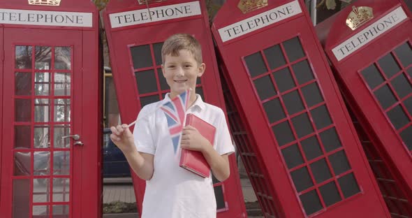 Slow Motion Portrait of Cute Boy Waving British Flag Standing Outdoors Alone Smiling Looking at